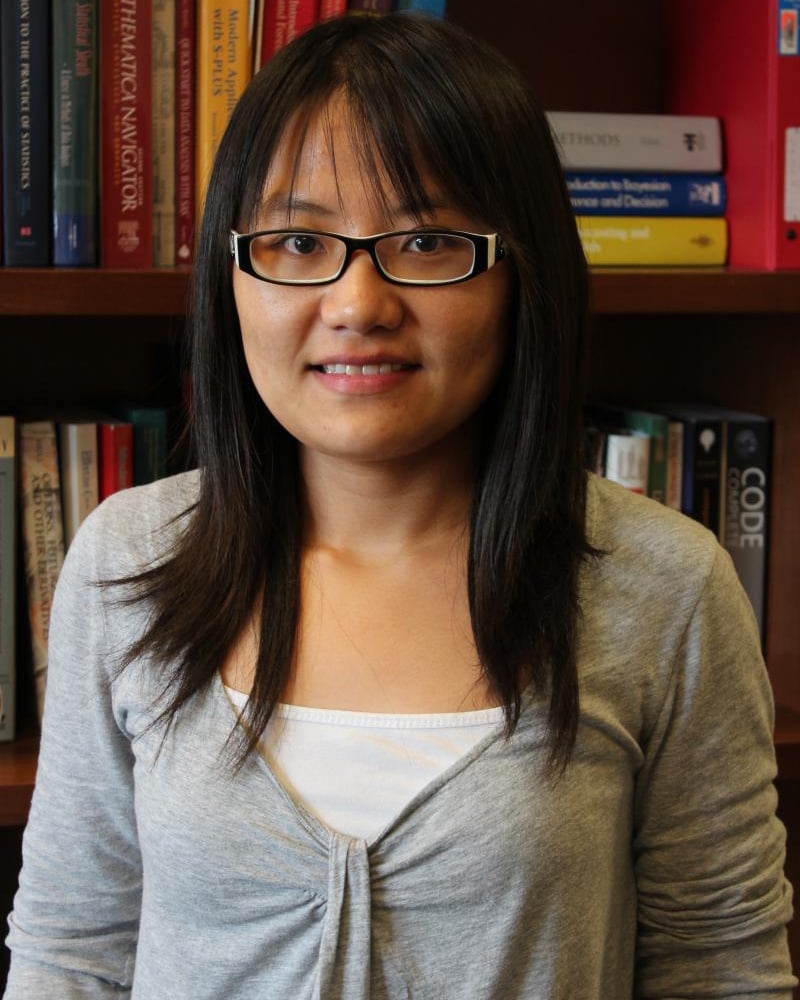 Woman with dark hair and glasses smiling.
