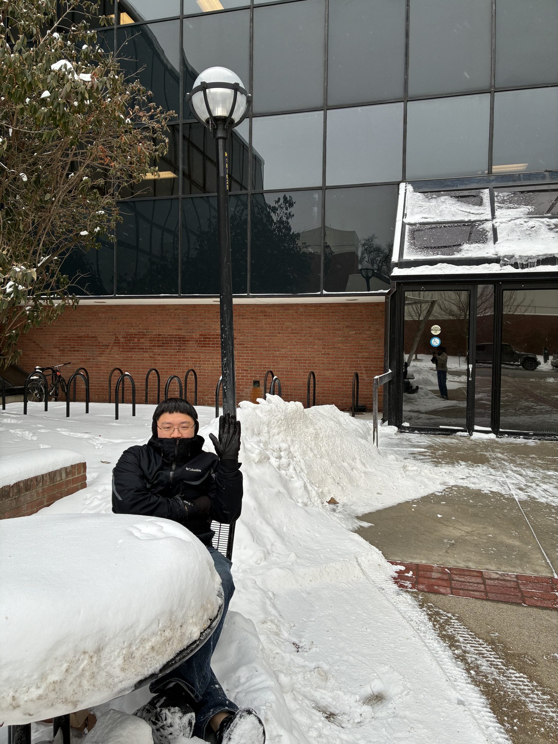 man bundled up in snow sitting outside ISR building
