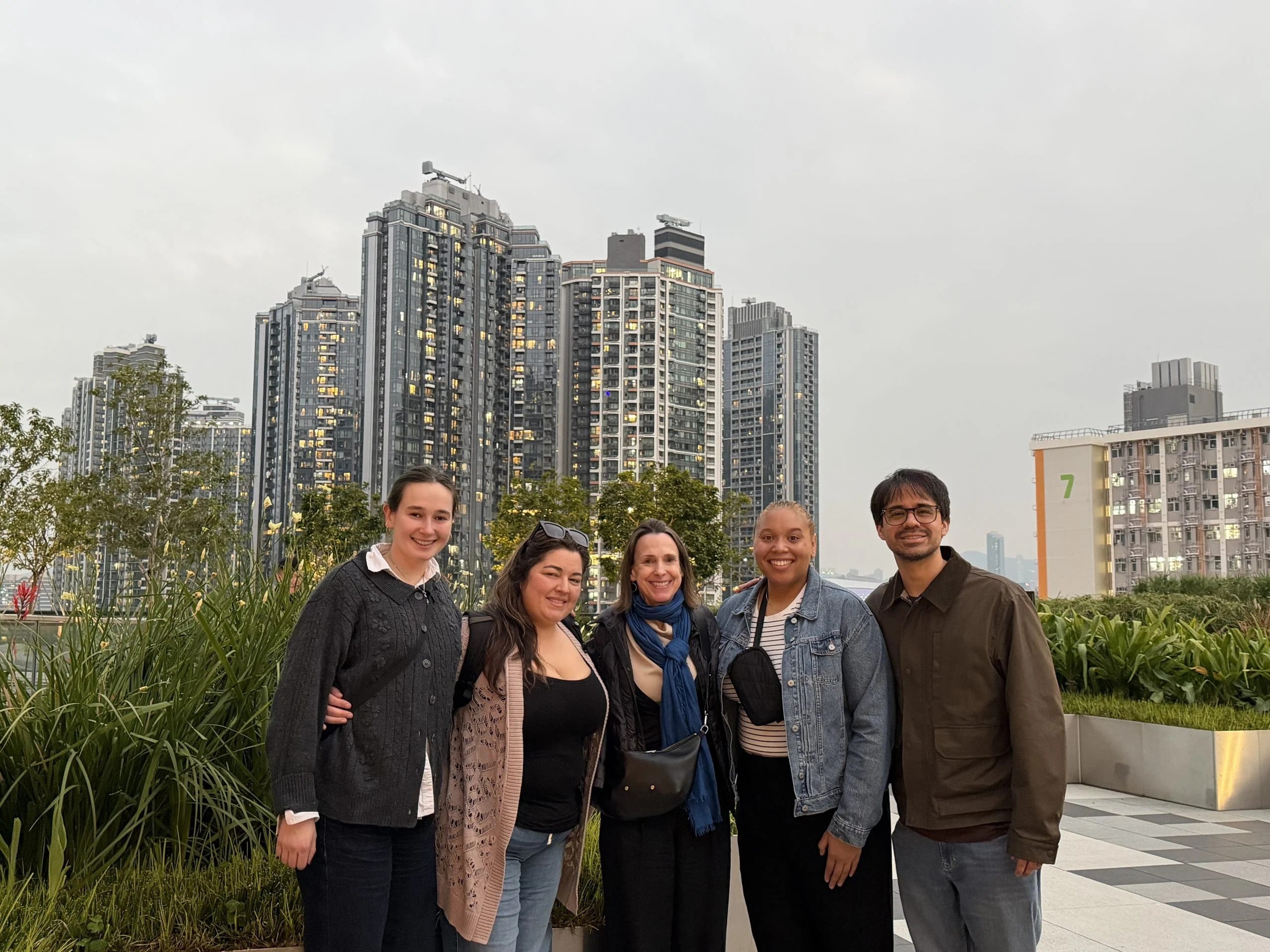 A group of people pose together in front of the Hong Kong cityscape.